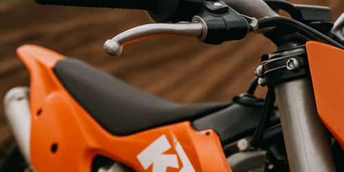 KTM crossmotor met close-up van een hoogwaardige gashendel op een modderig crosscircuit